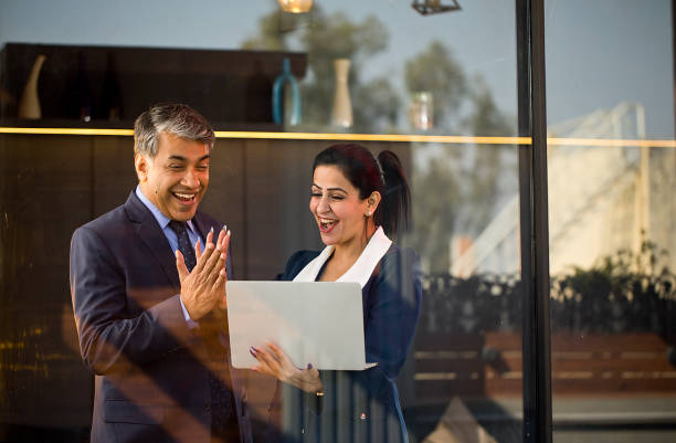 Businessman and businesswoman working together using laptop at office